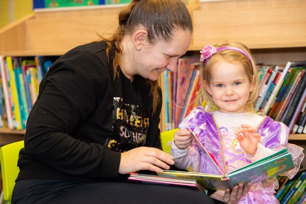 A woman reading with young girl in an Aura Library