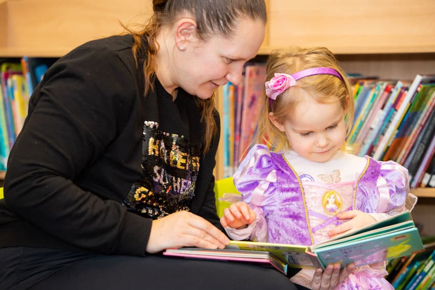Woman reading to a young girl in an Aura Wales Library