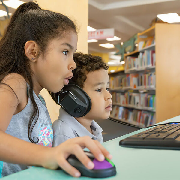 Two Young Children Using A Computer In A Library